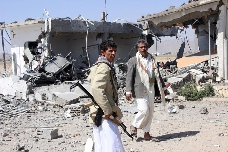 © Reuters. Milicianos Houthi em meio a destroços por conta de ataques aéreos na cidade de Saada