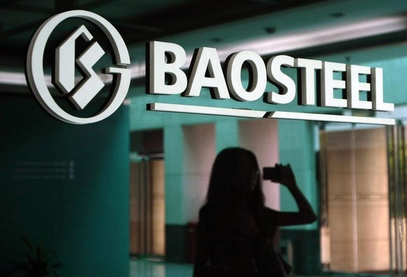 © Reuters. A woman is reflected on a wall with a company logo of Baosteel Group at an office in Shanghai