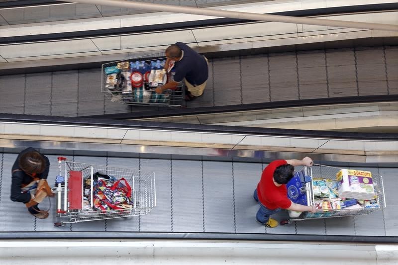 © Reuters. Customers push shopping trolleys on an escalator at the Bercy shopping centre in Charenton Le Pont, near Paris