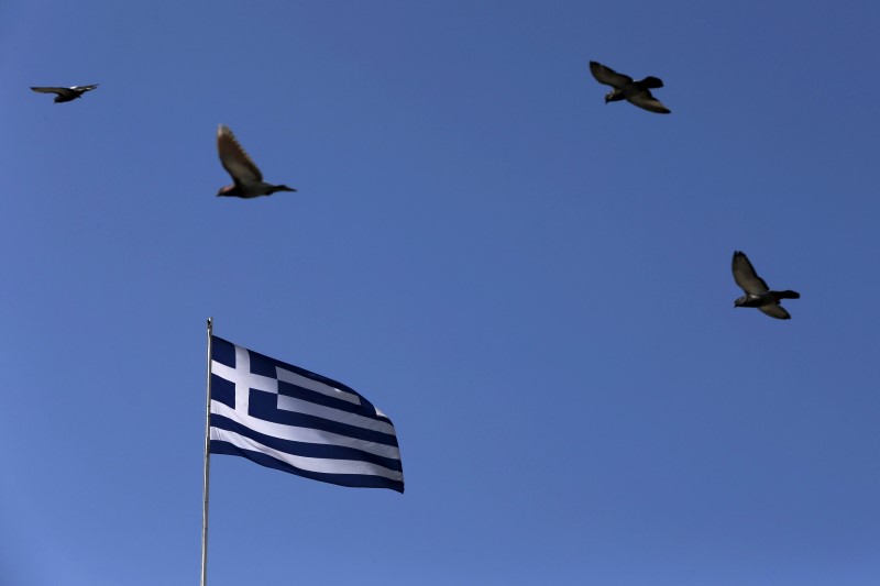 © Reuters. Pigeons fly over a fluttering Greek national flag in Athens