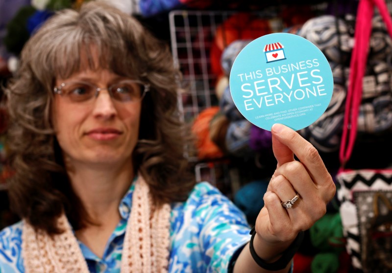 © Reuters. Business owner holds sticker to place outside her shop in Lafayette, Indiana