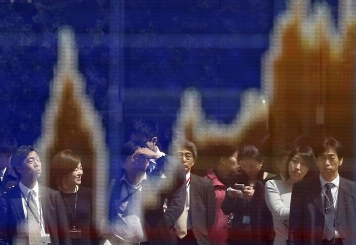 © Reuters. Passerbys are reflected on a graph showing recent Japan's Nikkei share average movements outside a brokerage in Tokyo