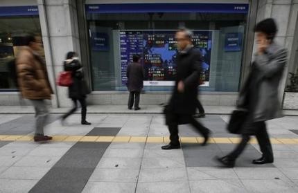 © Reuters. A man looks at an electronic board showing the stock market indices of various countries outside a brokerage in Tokyo