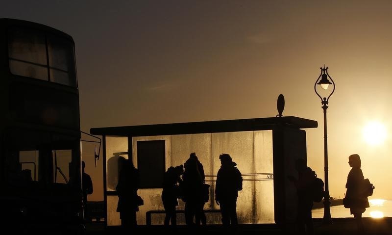 © Reuters. Commuters wait at a bus stop early in the morning near Howth in Dublin