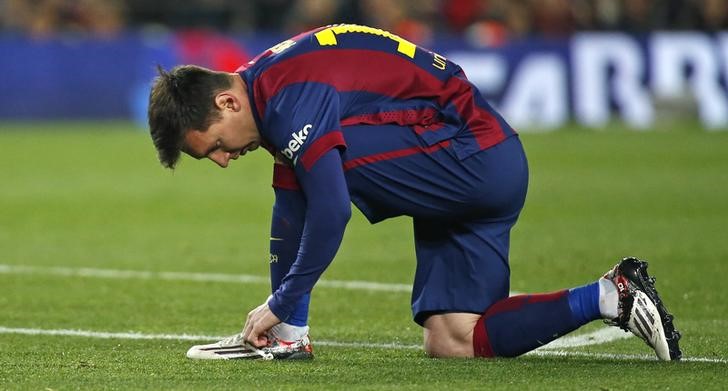 © Reuters. Barcelona's Messi ties his shoe laces during their Spanish first division "Clasico" soccer match against Real Madrid at Camp Nou stadium in Barcelona