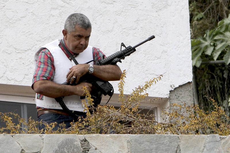 © Reuters. File photo of Angel Vivas, a retired army general and anti-President Nicolas Maduro protester, standing in his house with an automatic weapon as he resists being detained in Caracas 