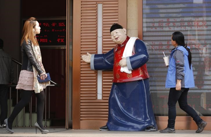 © Reuters. People walk past a statue, placed there to promote a restaurant, at a shopping district in Beijing