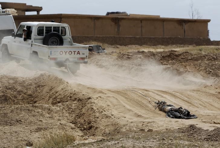 © Reuters. A vehicle belonging to Shiâ¬"ite militia fighters pulls the body of an Islamic State fighter, who was killed during clashes with Iraqi forces in Tikrit