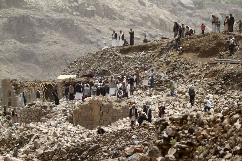 © Reuters. People stand on the rubble of houses destroyed by an air strike in Okash village near Sanaa