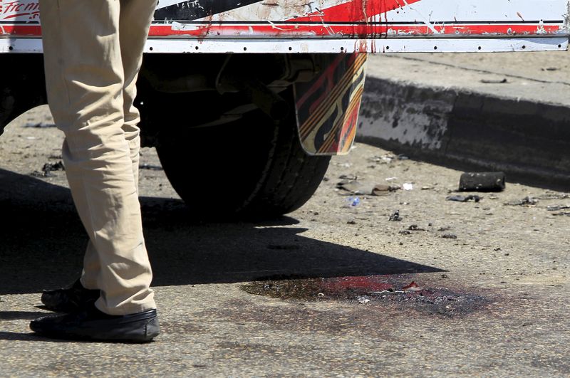 © Reuters. Bloodstains are seen on the ground as security officials inspect the scene of a car bomb blast on a bridge in Cairo district of Zamalek