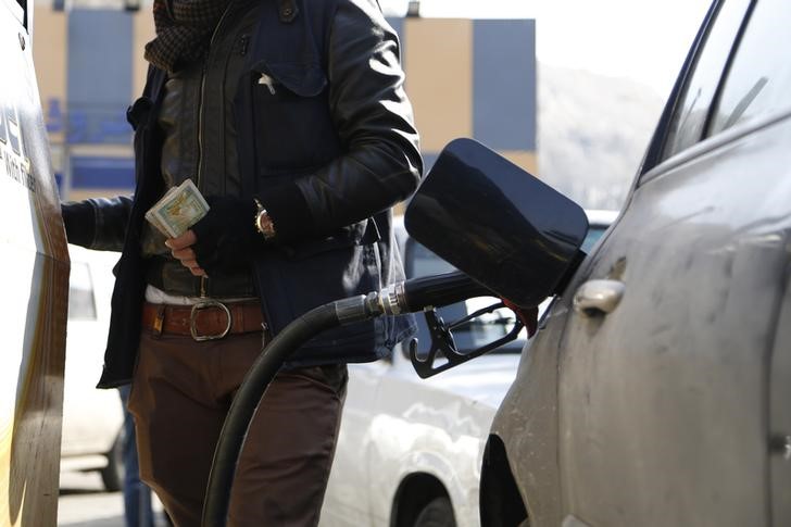 © Reuters. A man holds banknotes in his hand as he fills his car with fuel at Zahret Al Rabwah petrol station in Al-Rabweh, Damascus 