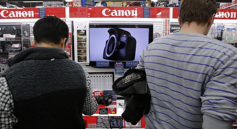 © Reuters. People look at Canon digital cameras at an electronics retail store in Tokyo