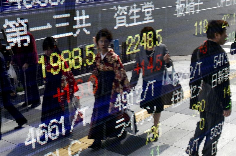 © Reuters. Women wearing Hakama, or Japanese traditional Kimono, are reflected in an electronic board, showing various stock prices, outside a brokerage in Tokyo
