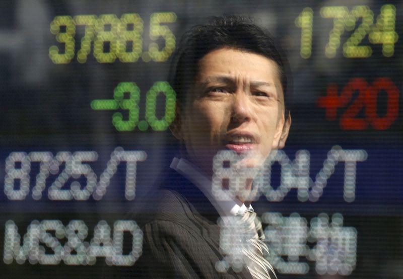 © Reuters. A man is reflected on an electronic stock quotation board outside a brokerage in Tokyo