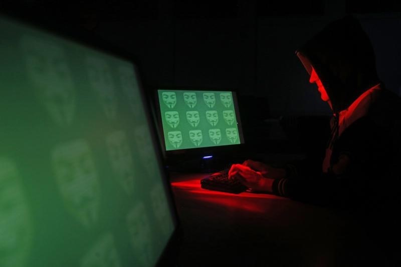 © Reuters. Man poses in front of on a display showing the word 'cyber' in binary code, in this picture illustration taken in Zenica