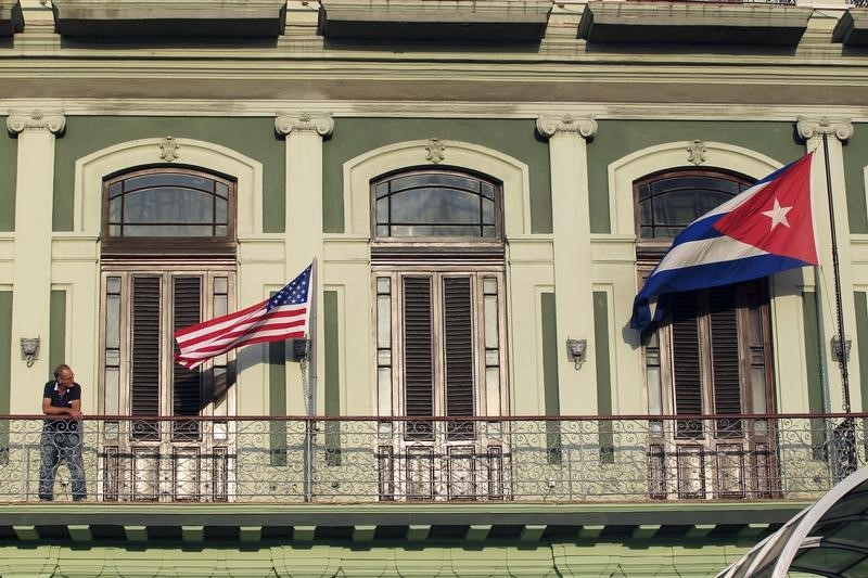 © Reuters. Man stands near national flags of U.S. and Cuba on balcony of a hotel being used by first U.S. congressional delegation to Cuba since change of policy announced by U.S. President Obama, in Havana