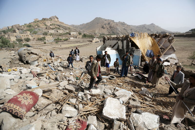 © Reuters. People gather on the wreckage of a house destroyed by an air strike in the Bait Rejal village west of Yemen's capital Sanaa