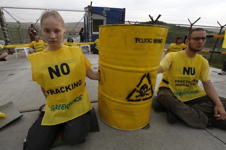 © Reuters. Greenpeace activists sit chained in front of a U.S. oil major Chevron's drilling site for shale gas during a protest, in the village of Pungesti