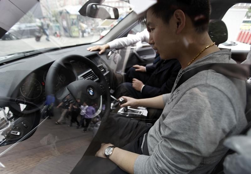 © Reuters. A man sits in a newly bought BMW X3 car at a dealership in central Beijing