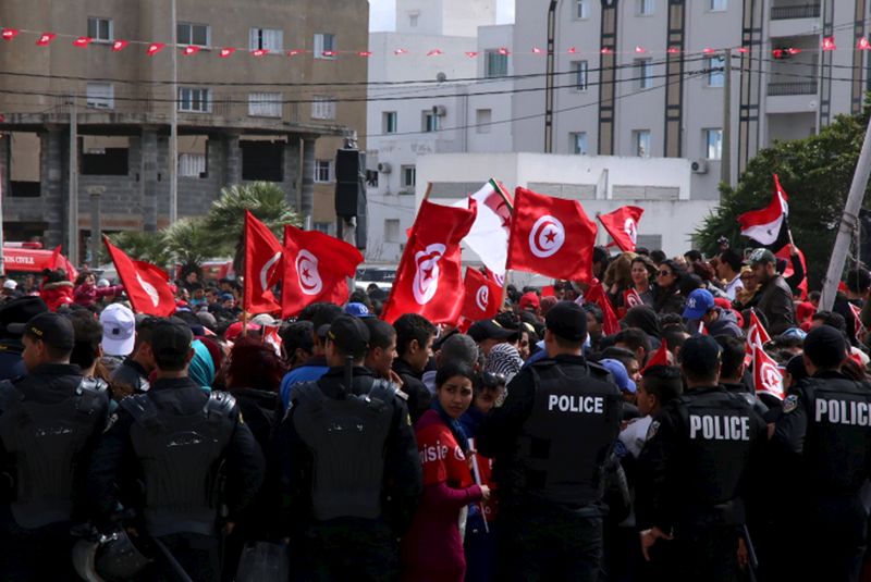 © Reuters. Tunisians wave their national flags during a march against extremism outside the Bardo Museum in Tunis