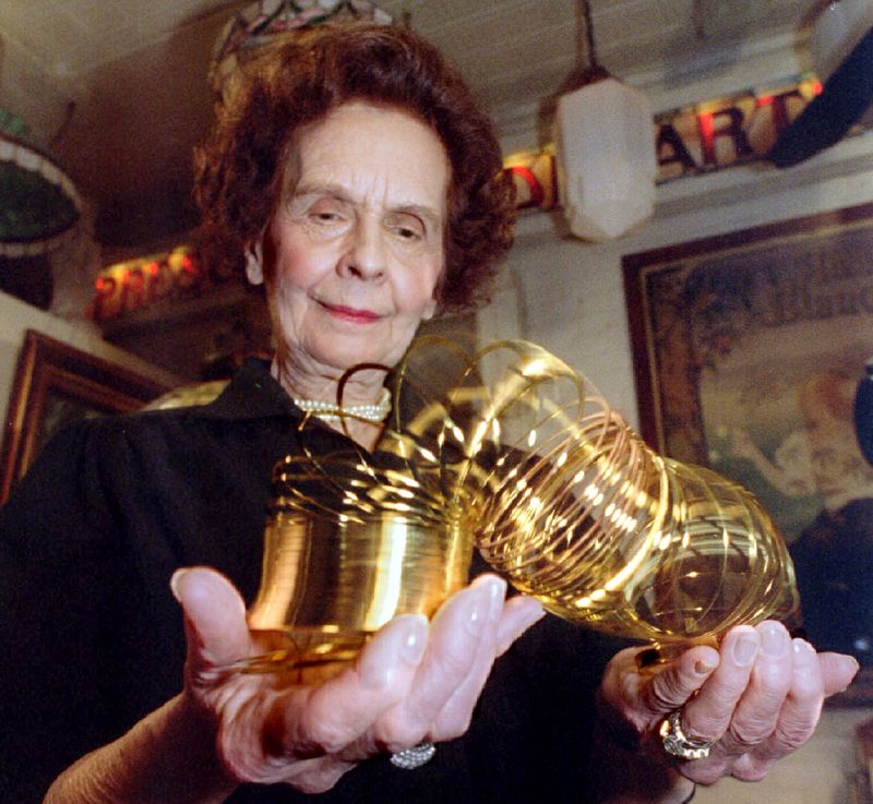 © Reuters. busFile photo of Betty James wife of Slinky creator Richard James displays a 50th anniversary gold commemorative edition of the Slinky toy in New York