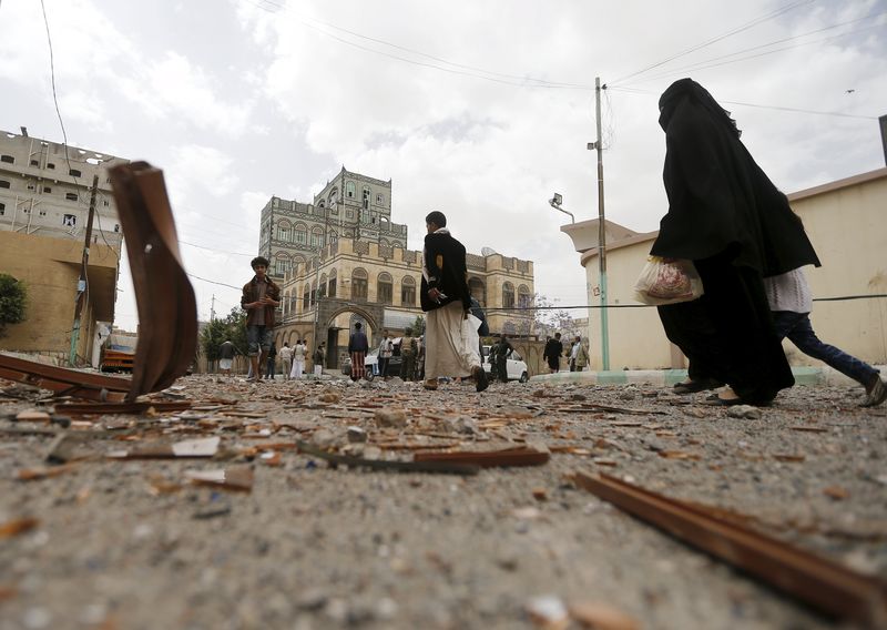 © Reuters. People walk at site of airstrike in Sanaa