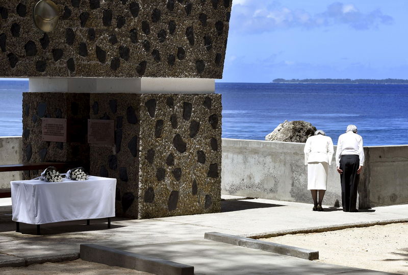 © Reuters. Japan's Emperor Akihito and Empress Michiko bow toward to Angaur Island after they offered flowers to the cenotaph for war dead in the western Pacific area, on Palau's Peleliu Island