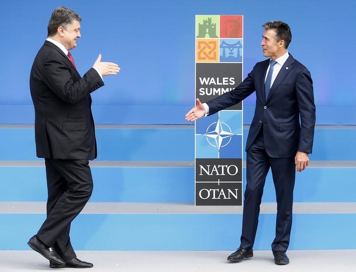 © Reuters. NATO Secretary-General Anders Fogh Rasmussen greets Ukranian President Petro Poroshenko at the start of the  NATO summit at the Celtic Manor resort, near Newport