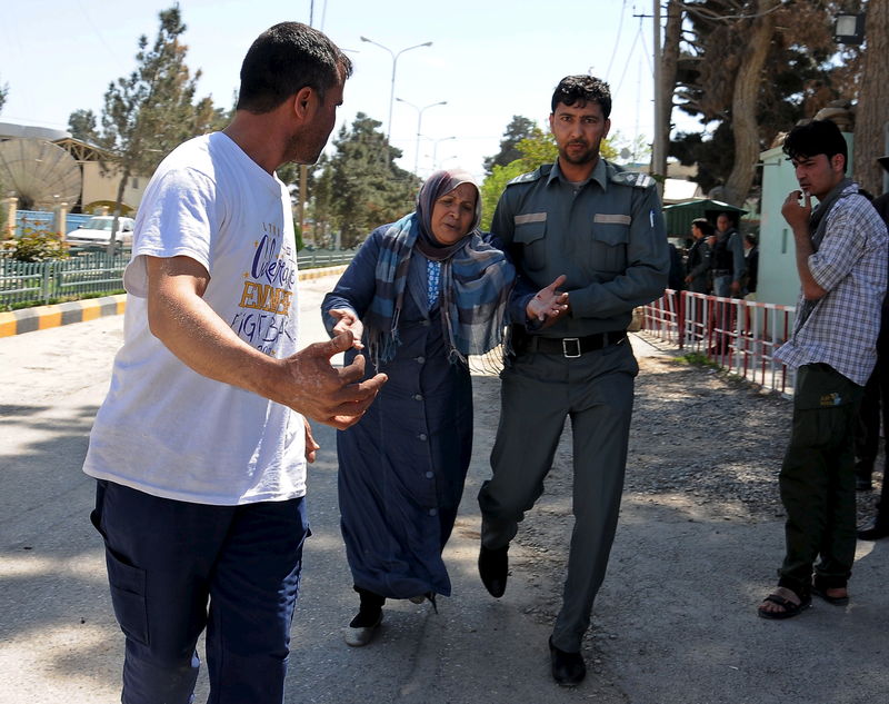 © Reuters. Policial afegão ajuda mulher após ataque em Mazar-i-Sharif