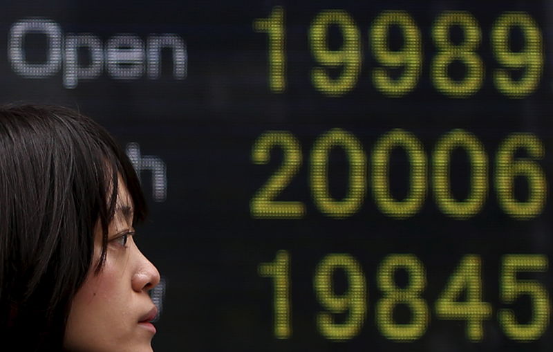 © Reuters. A pedestrian walks past an electronic board showing the Japan's Nikkei averages outside a brokerage in Tokyo