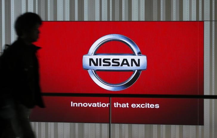 © Reuters. A man walks past a screen displaying the brand logo of car maker Nissan at a showroom in Yokohama