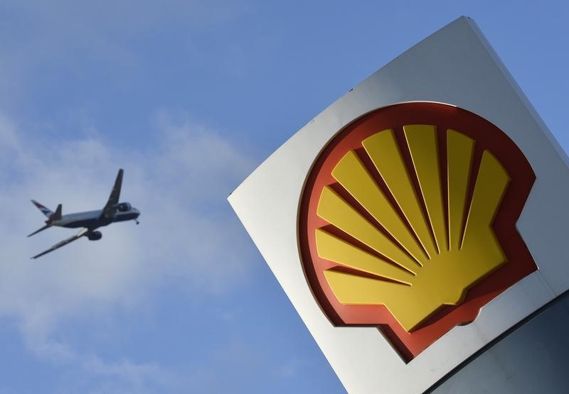 © Reuters. A passenger plane flies over a Shell logo at a petrol station in west London