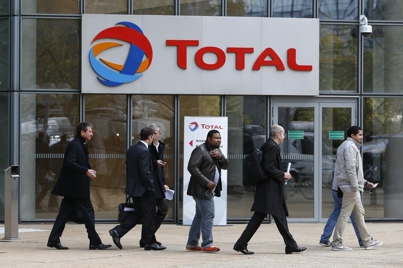 © Reuters. People walk past the entrance of French oil giant Total headquarters in the financial and business district of la Defense near Paris