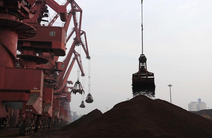 © Reuters. Cranes unload iron ore from a ship at a port in Rizhao