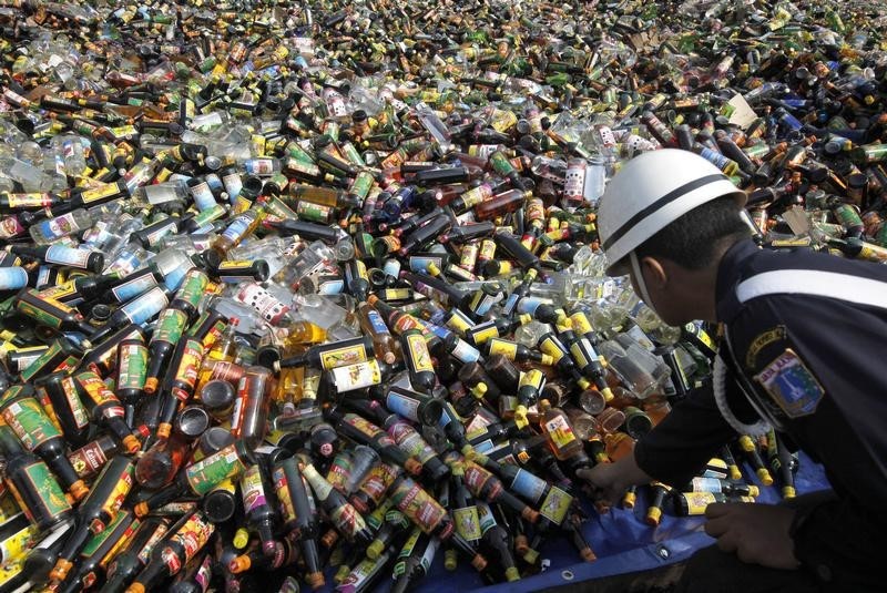 © Reuters. A security officer checks bottles of alcohol confiscated from street shops before being destroyed in Jakarta