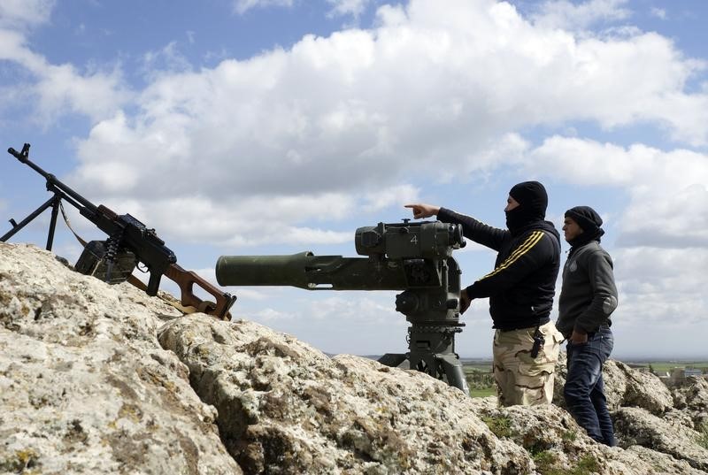 © Reuters. A rebel fighter of the Southern Front of the Free Syrian Army gestures while standing with his fellow fighter near their weapons at the front line in the north-west countryside of Deraa