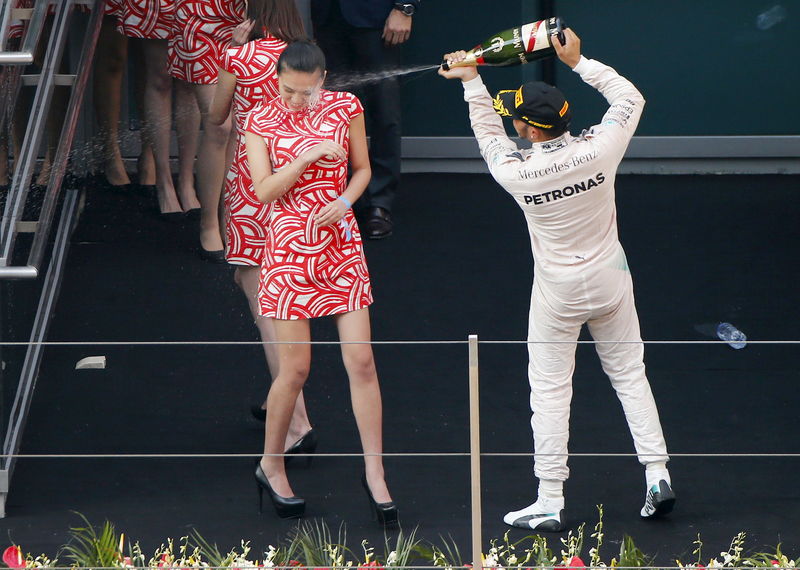 © Reuters. Lewis Hamilton, da Mercedes, joga champagne no rosto de moça no pódio do GP da China de F1, em Xangai