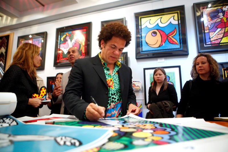 © Reuters. Artist Romero Britto signs posters at a gallery in New York