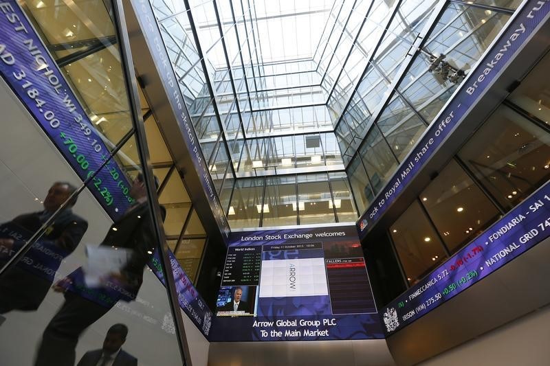 © Reuters. People pass electronic information boards at the London Stock Exchange in the City of London