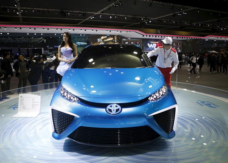 © Reuters. A model poses next to a Toyota Motor's concept car FCV as a worker wipes the car at the Seoul Motor Show 2015 in Goyang