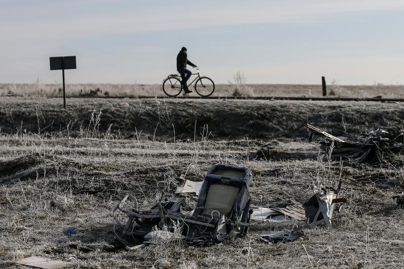 © Reuters. A man rides bicycle past wreckage of MH17, Malaysia Airlines Boeing 777 plane, at site of plane crash near village of Hrabove (Grabovo) in Donetsk