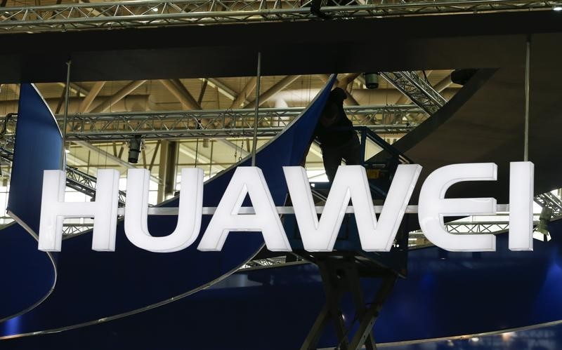 © Reuters. A worker adjusts the logo at the stand of Huawei at the CeBIT trade fair in Hanover