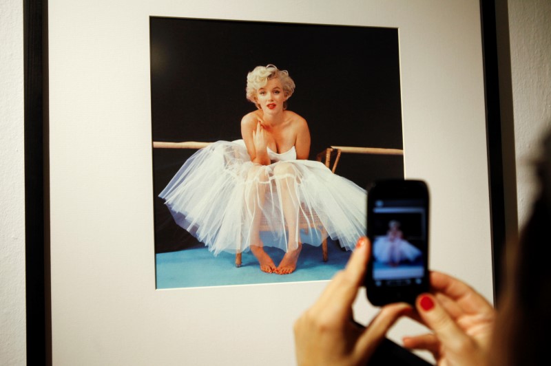 © Reuters. A woman takes picture of a framed Marilyn Monroe photo at gallery in Warsaw