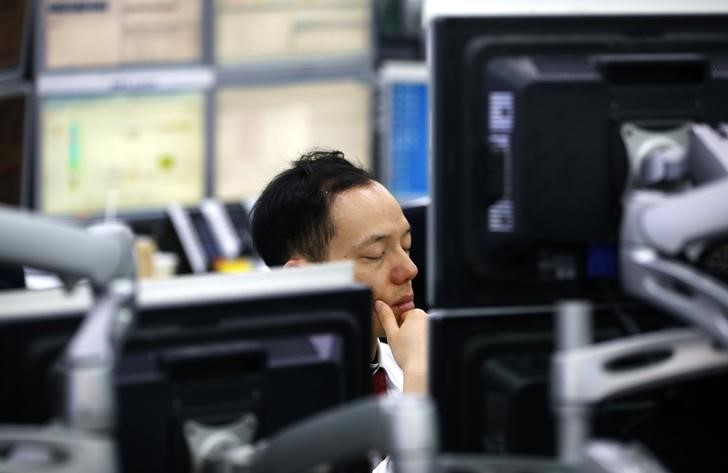 © Reuters. A currency dealer sleeps in front of screens as he works at a dealing room of a bank in Seoul