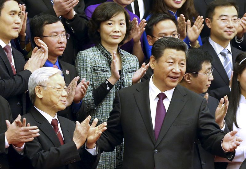 © Reuters. China's President Xi gestures to Vietnam's Communist Party General Secretary Nguyen as they pose for a group photo with Chinese and Vietnamese youths at the Great Hall of the People in Beijing