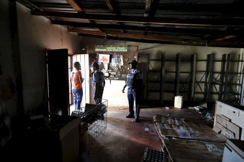 © Reuters. Police officers chat with a foreign national as they help him evacuate his shop for fear of attacks in Primrose outside Johannesburg