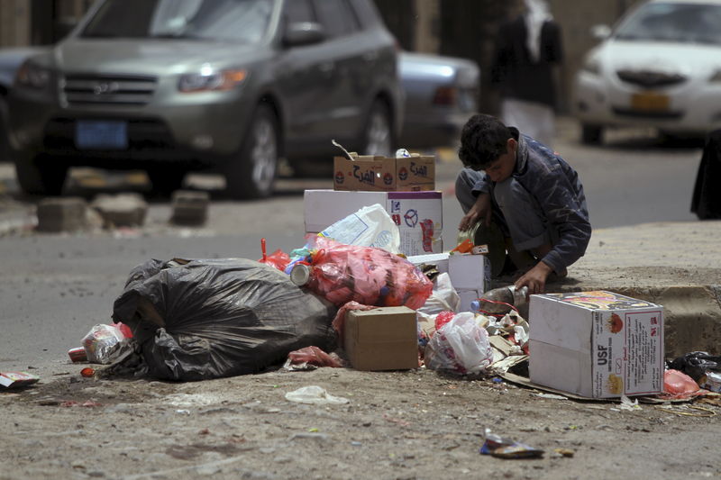 © Reuters. Boy searches for food amongst litter on a streetside in Sanaa