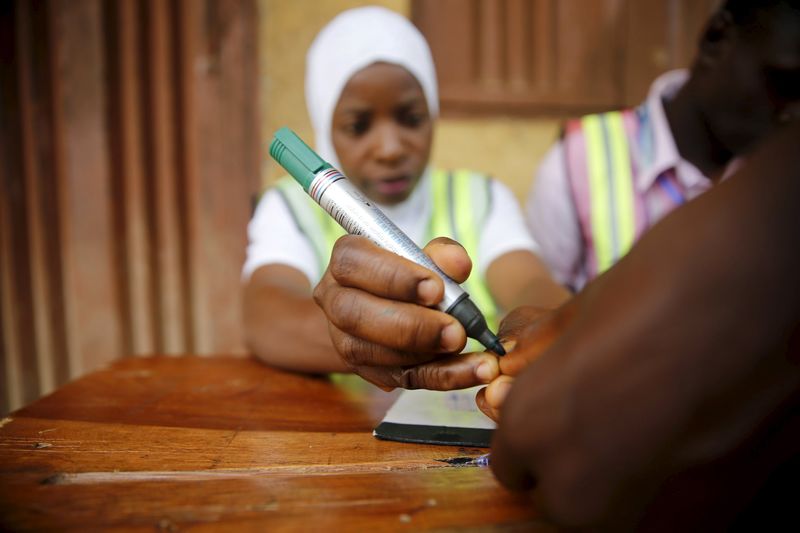 © Reuters. An electoral officer marks the thumb of a voter with ink at the start of voting during governorship election in Epe district in Nigeria's commercial capital Lagos