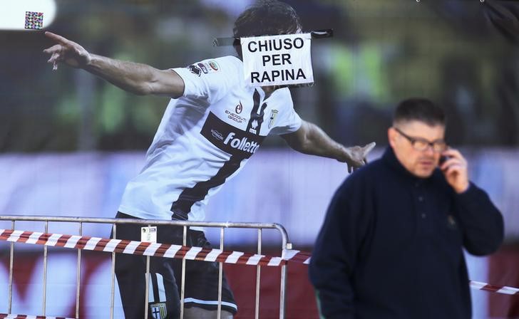 © Reuters. Homem telefona em frente ao pôster de um jogador do Parma