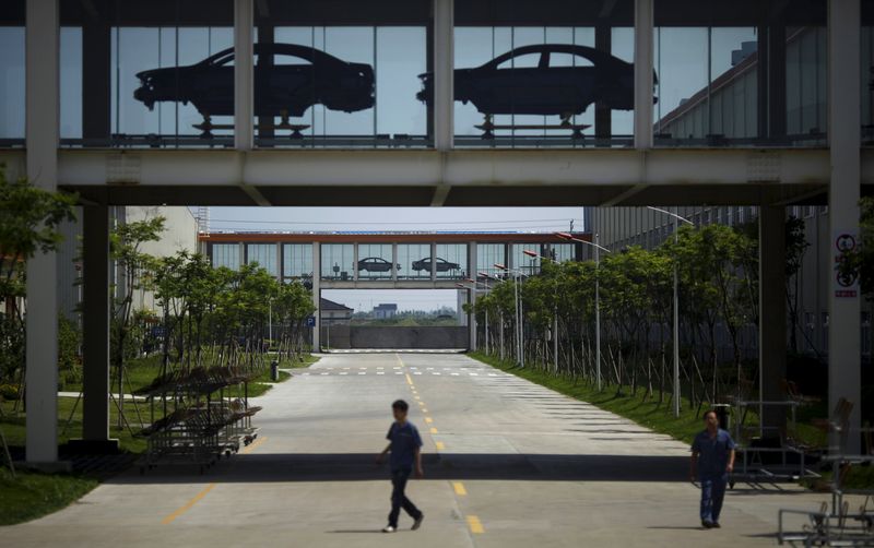 © Reuters. File photo of employees walking under a car assembly line at Geely Automobile Corporation in Cixi